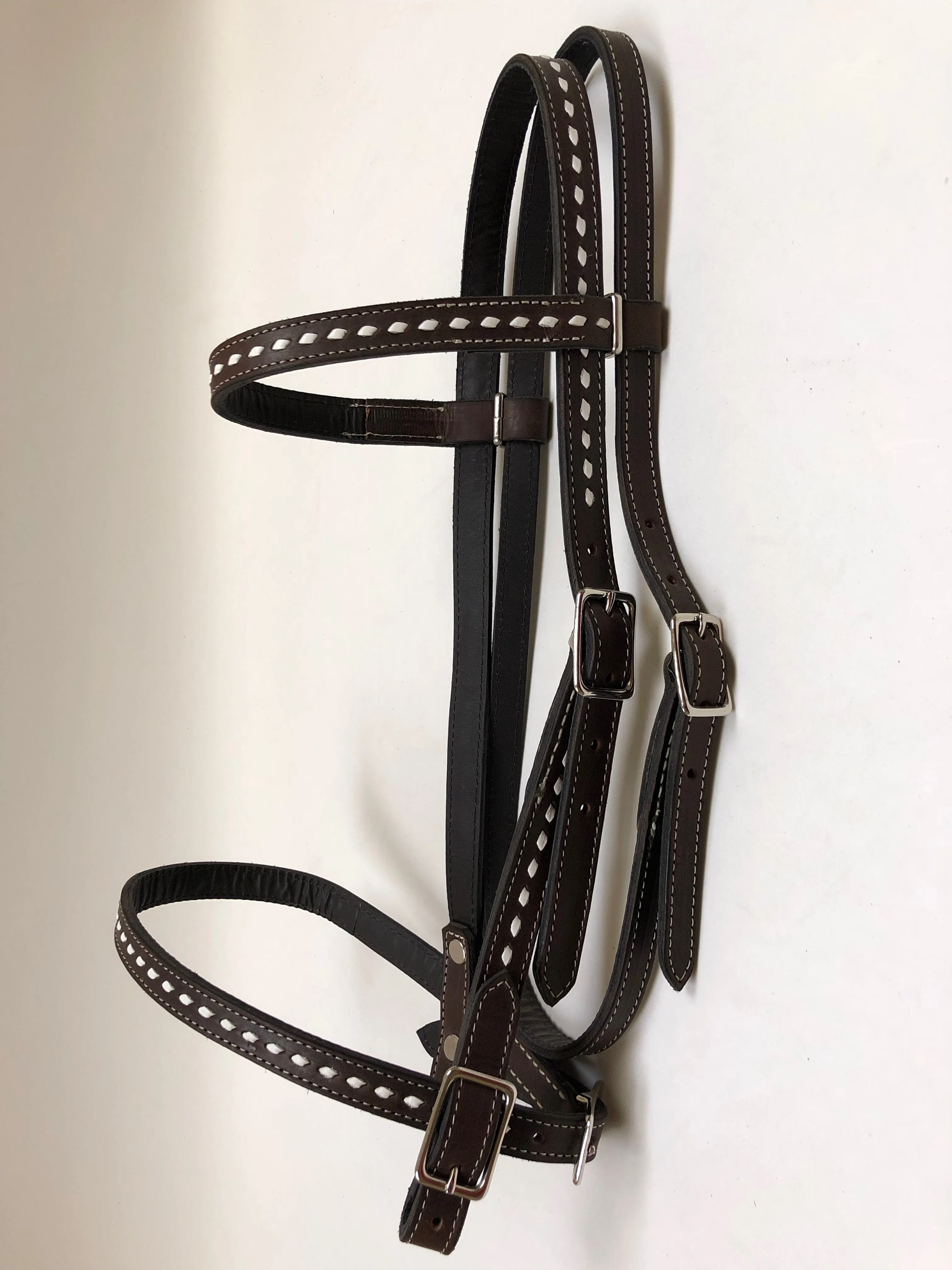 Dark brown handmade bridles and reins with buck stitch and white lace