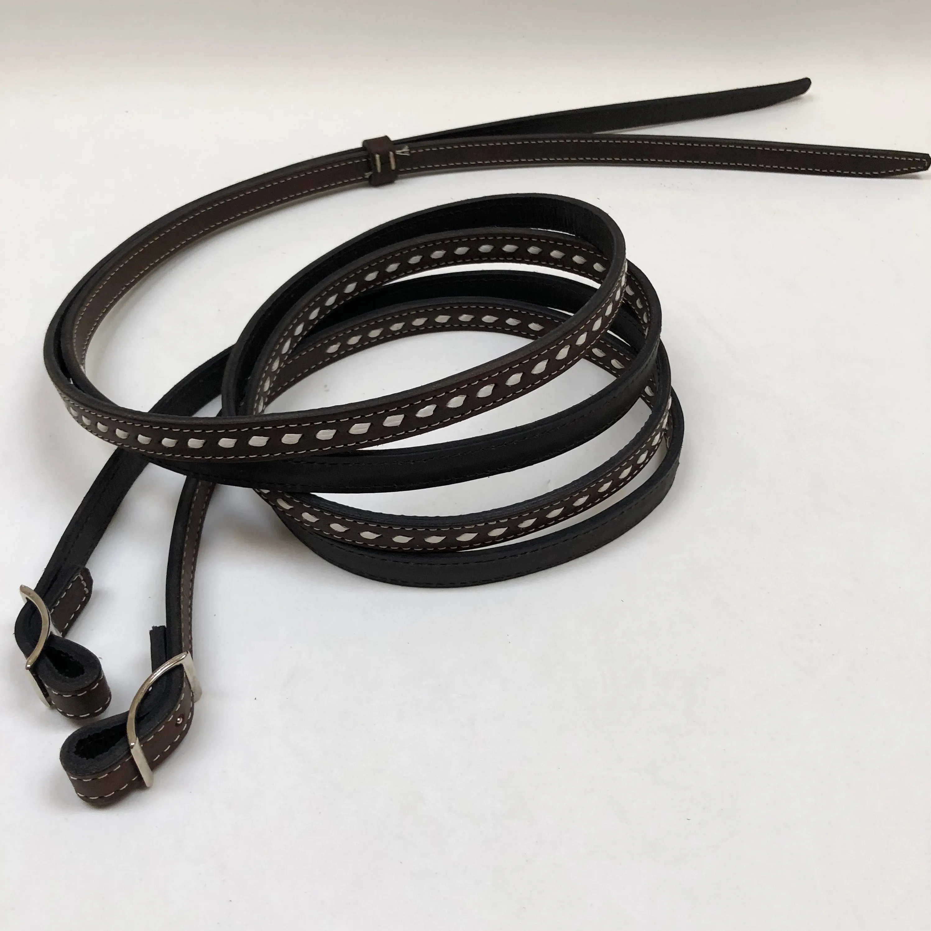 Dark brown handmade bridles and reins with buck stitch and white lace